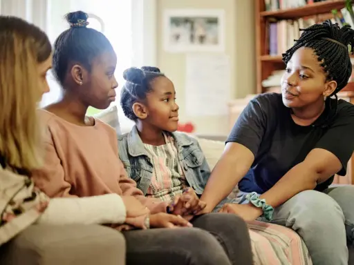 Eine Familie spricht auf dem Sofa. Das jüngste Kind, das oft als hyperaktives Kind beschrieben wird, hört aufmerksam zu.