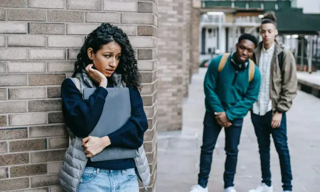 Ein Mädchen fühlt sich unwohl, als zwei Jungen sie anstarren. Eine Szene, die an eine **kurzgeschichte mobbing grundschule** erinnert, wo Ausgrenzung und Angst herrschen.