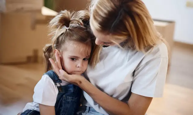 Mutter tröstet ihr Kind, das Angst vor anderen Kindern hat.