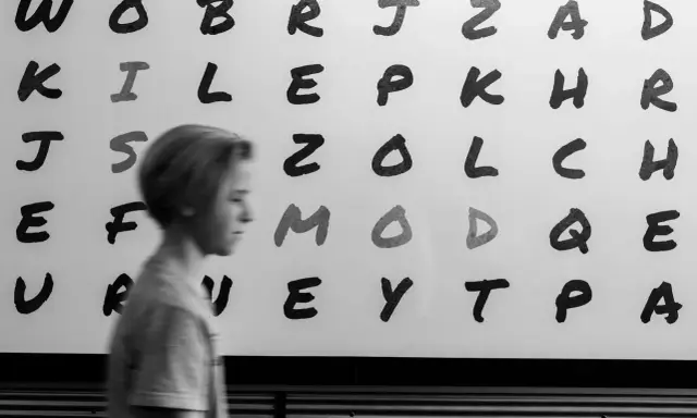 Junge vor Buchstabenwand, die LRS-Symptome in der 2. Klasse verdeutlichen könnte.