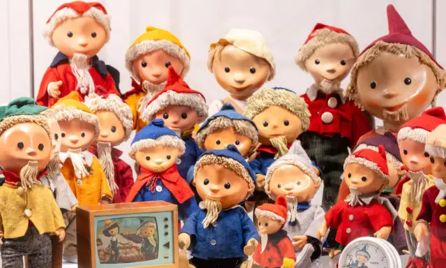 Eine Sammlung von Sandmann-Charakteren in bunten Kostümen, einige mit Bart und Mützen, stehen dicht gedrängt.