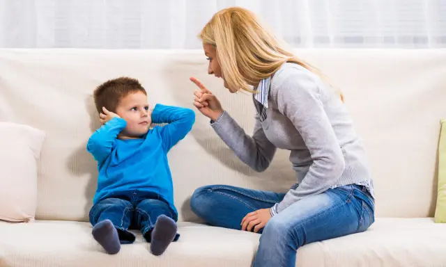 Mutter schimpft mit Sohn, der sich die Ohren zuhält. Ein typischer Streit mit Eltern, der die Geduld auf die Probe stellt.