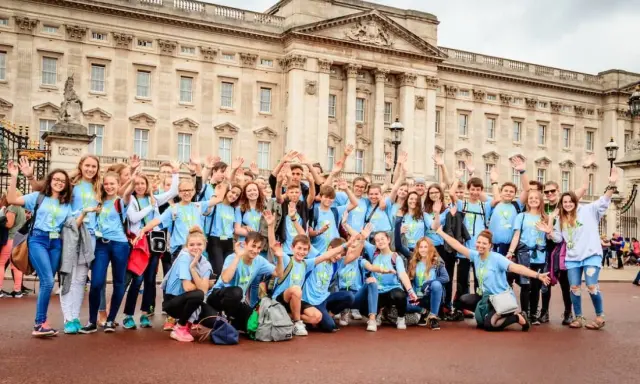 Eine fröhliche Gruppe Jugendlicher vor dem Buckingham Palace, bereit für ihr sprachcamp englisch.