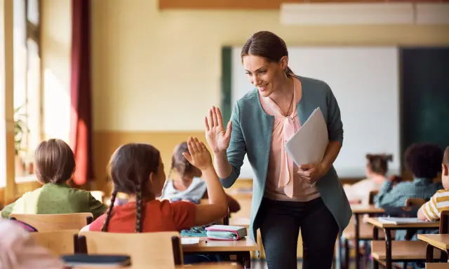 Lehrerin gibt einem Grundschüler einen High-Five. So kann man Kinder zum Lernen motivieren.