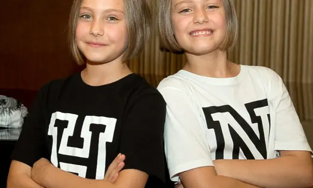 Zwei Mädchen mit kurzen Haaren, die T-Shirts mit den Buchstaben "H" und "N" tragen. Man fragt sich, wie alt sind Hanni und Nanni wohl?