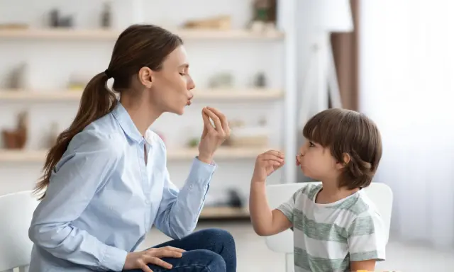 Eine Frau und ein Kind machen Lippenbewegungen. Dies kann ein Hinweis sein, um autismus erkennen kind.