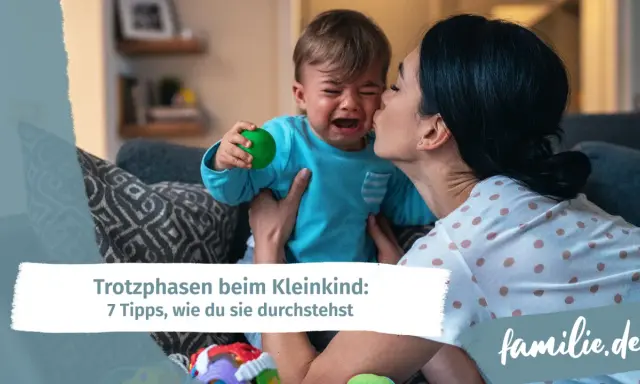 Mutter tröstet weinendes Kind, das einen grünen Ball hält. Ein Beispiel für den emotionalen quotient eines Kleinkindes.