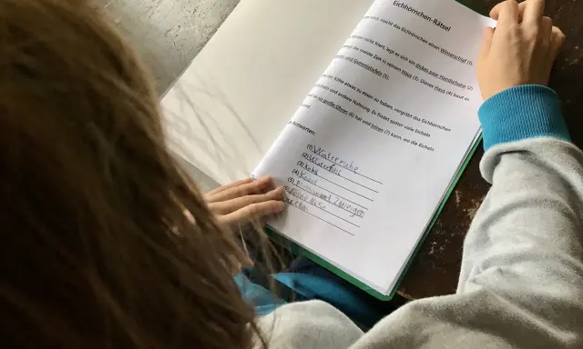 Kind macht Hausaufgaben und löst ein Eichhörnchen-Rätsel.
