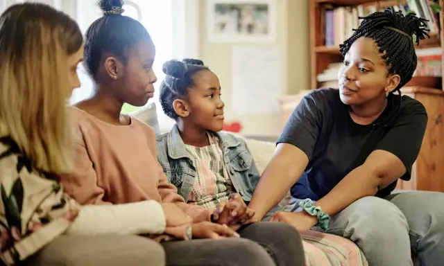 Eine Familie spricht auf dem Sofa. Das jüngste Kind, das oft als hyperaktives Kind beschrieben wird, hört aufmerksam zu.