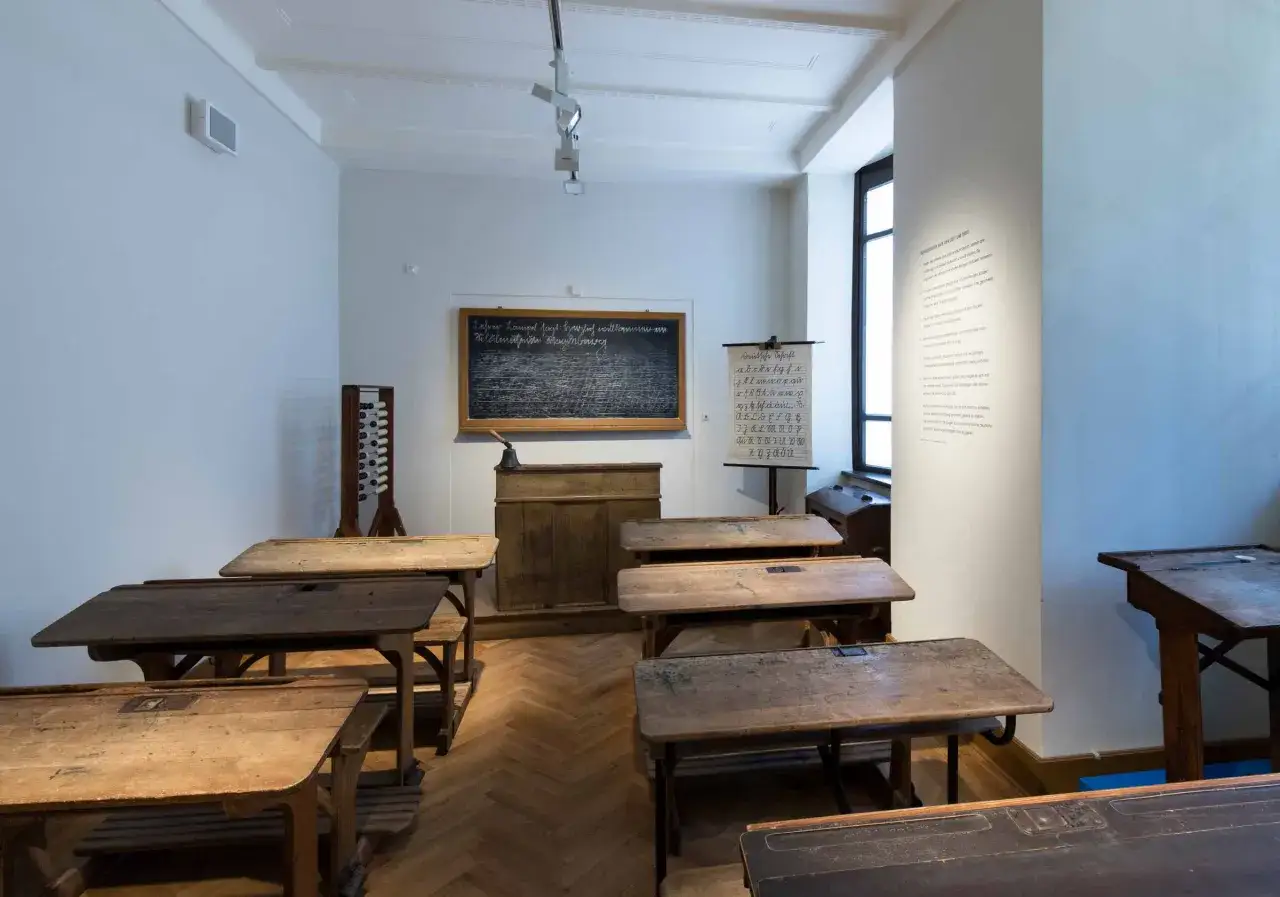 Klassenzimmer um 1900 mit alten Schulb&auml;nken, Tafel und Lehrtafel. Ein Blick in die Vergangenheit der Schule.