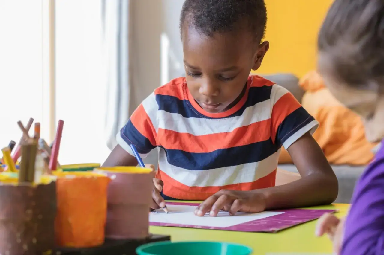 Konzentrierter Junge malt im Kindergarten. Kreativität und Motivation bei Kindern im Kindergarten fördern.