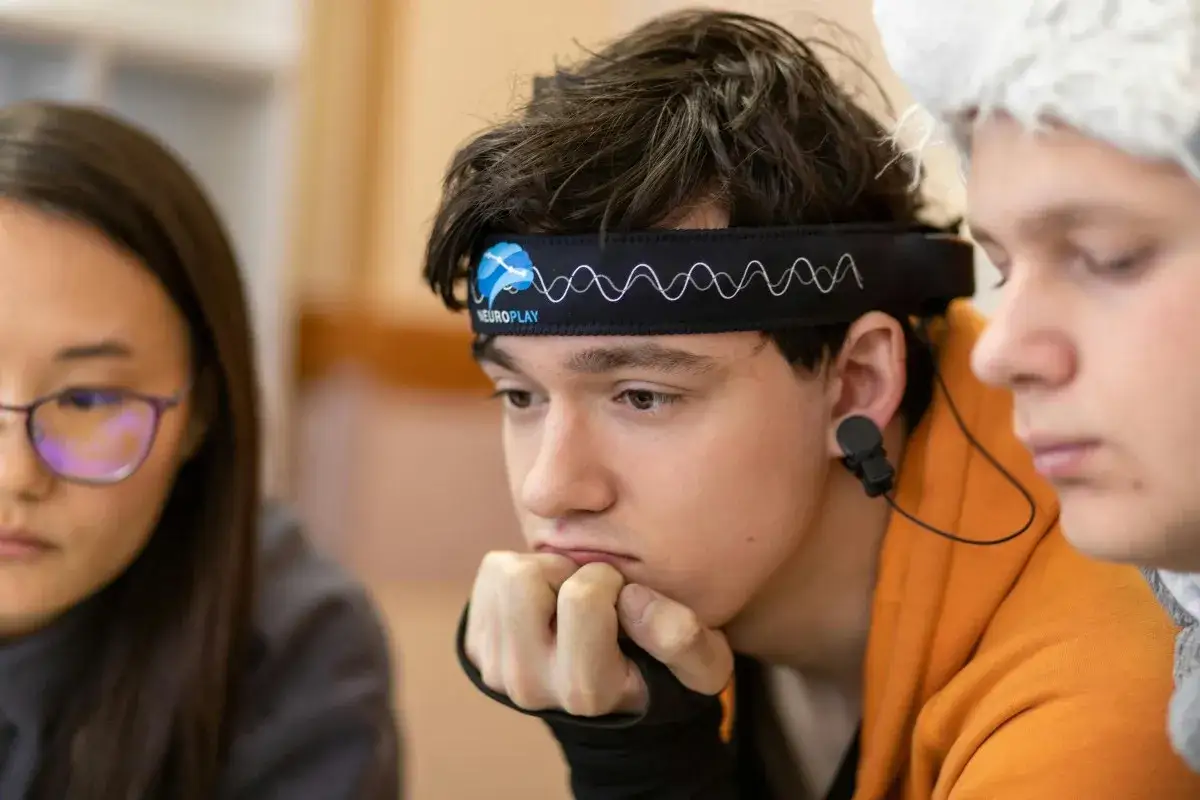 Junge mit EEG-Kopfband, das auf ADHS-Forschung hindeutet, blickt nachdenklich.