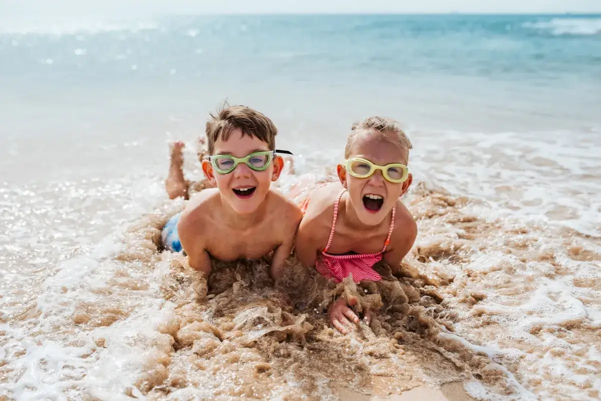 Zwei Kinder mit Schwimmbrillen planschen lachend im Wasser. Ein perfekter sommer auf solupp!