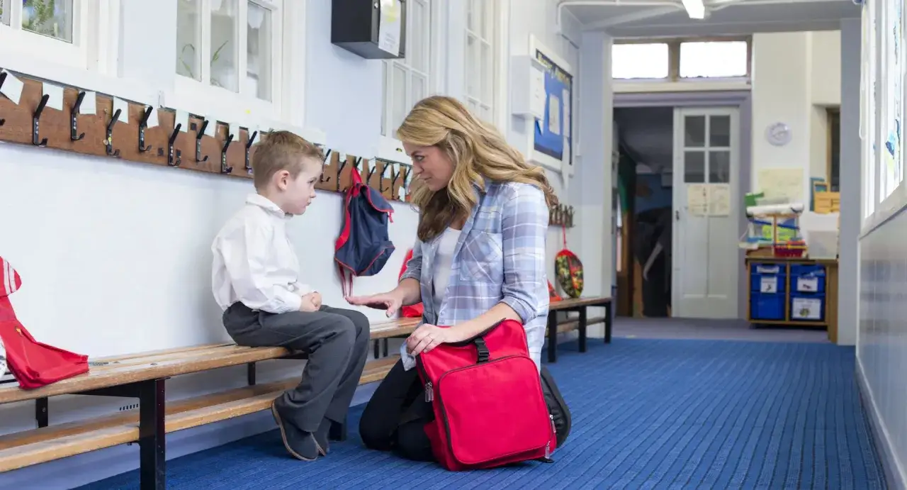 Lehrerin spricht mit einem Jungen über Probleme mit Eltern. Was tun? Sie sitzt auf dem Boden, er auf einer Bank.