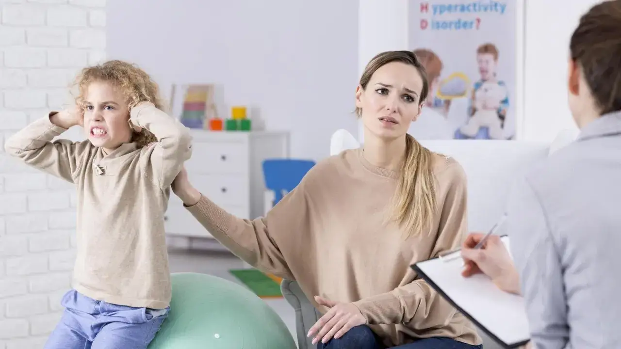 Besorgte Mutter teilt ihre Erfahrungen mit Ritalin bei Kindern mit einem Therapeuten, w&auml;hrend ihr Sohn frustriert die Ohren zuh&auml;lt.