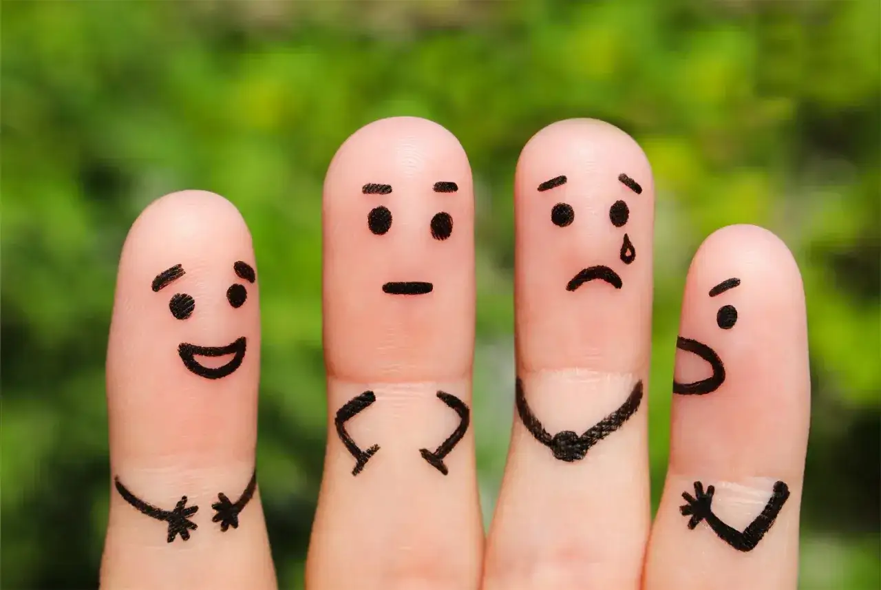 Vier bemalte Finger mit Gesichtern: Einer lacht, einer ist neutral, einer weint und einer schreit. Ein Beispiel für liebevollen Umgang mit Kindern, der alle Gefühle zulässt.