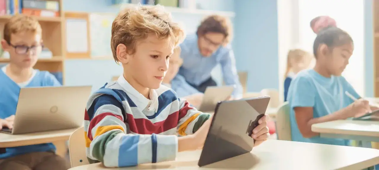 Schüler lernen mit Tablets und Laptops. Der Medieneinsatz im Unterricht ist hier gut sichtbar.