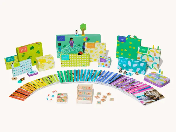 Bunte Lernspiele und Karten fördern spielerisch lesen lernen. Kleine Holzfiguren und bunte Boxen laden zum Entdecken ein.