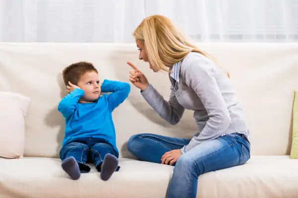Mutter schimpft mit Sohn, der sich die Ohren zuhält. Ein typischer Streit mit Eltern, der die Geduld auf die Probe stellt.